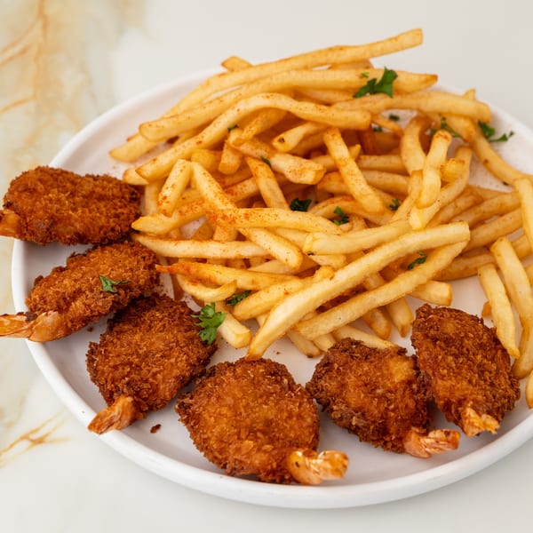 Golden fried shrimp and french fries with paprika and parsley on a white plate.